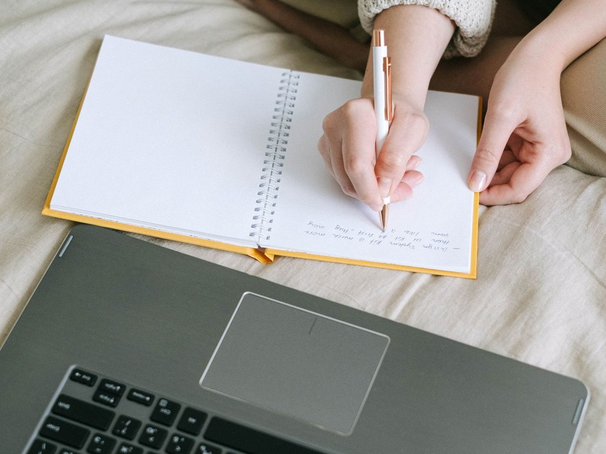 Aufgeschlagenes Notizbuch mit handschriftlichen Notizen neben einem Laptop — Mitschreiben während des Minikurses